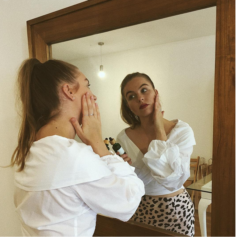 Hands warming a few drops of botanical facial oil as part of the Roseroma morning skincare ritual, preparing for gentle massage and mindful skincare.